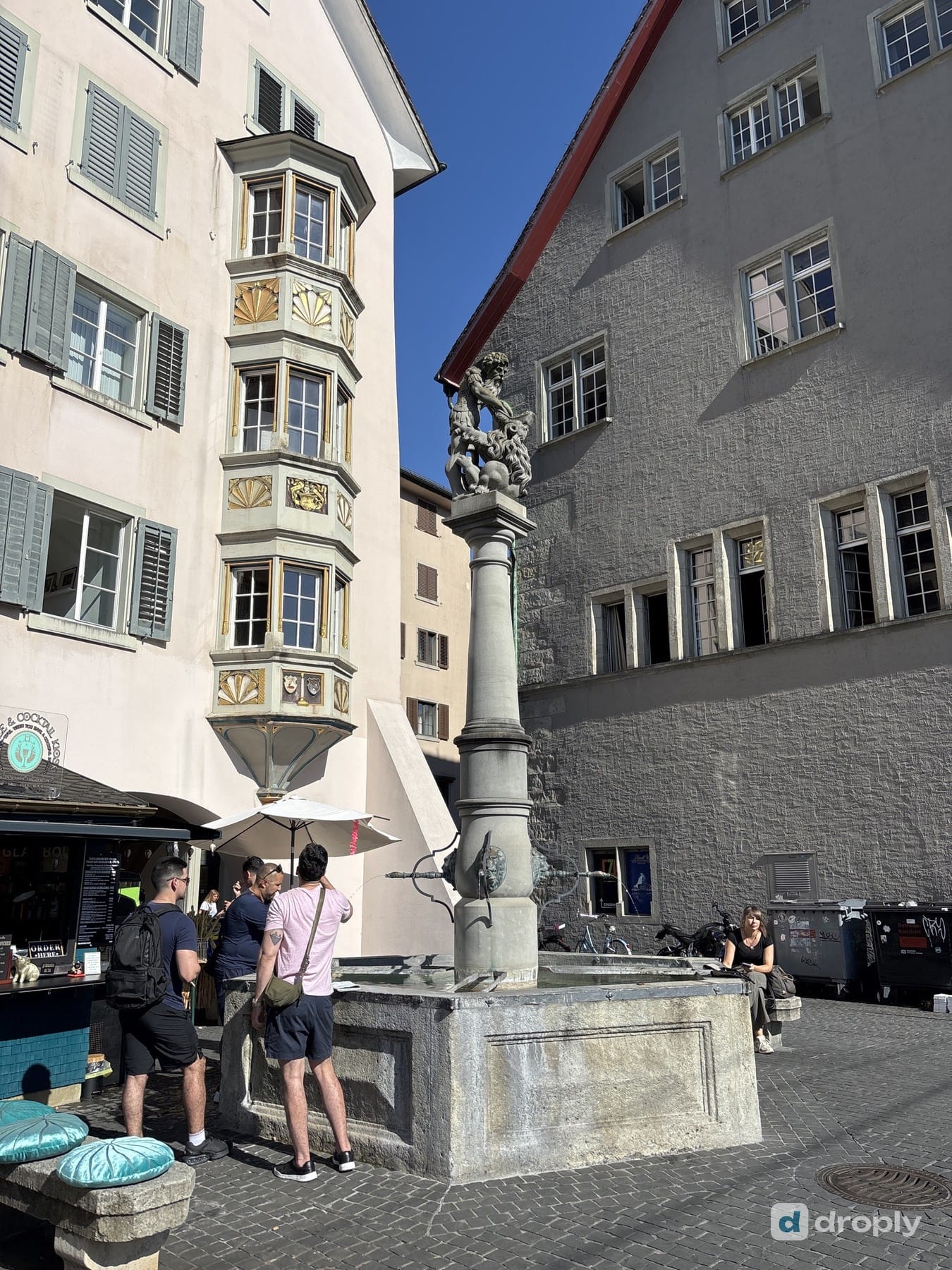 A drinking fountain in front of a painted bay-window facade at Fischmarkt in Zurich's old town