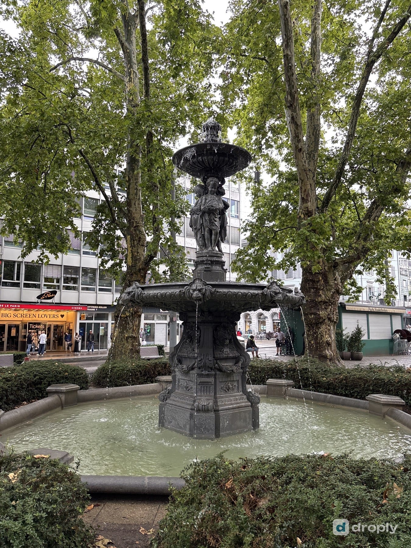 A cast-iron, multi-tiered fountain under trees at Stadelhofen in Zurich