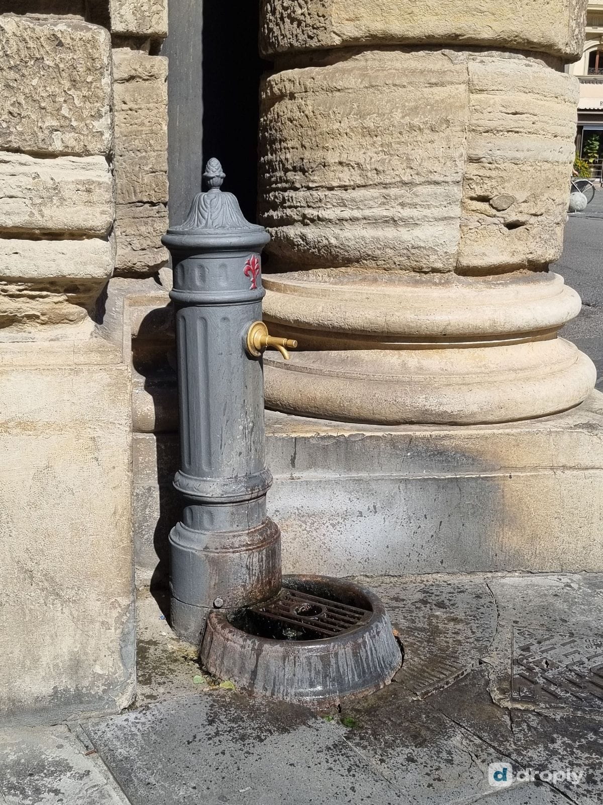 A tall iron drinking fountain on a stone column in Piazza della Repubblica, Florence