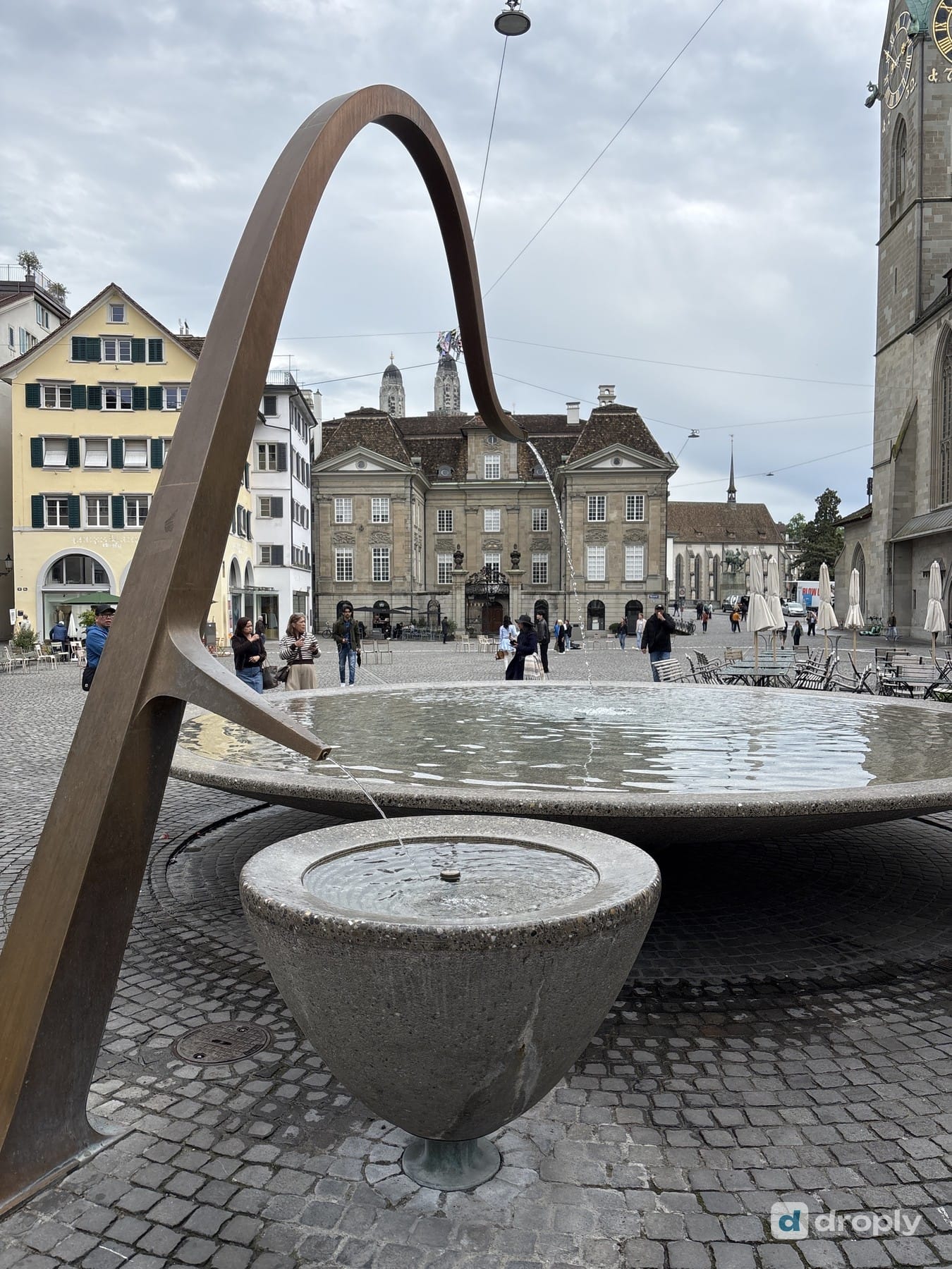 The modern Münsterhofbrunnen with a wide metal arc in front of the Münsterhof square in Zurich