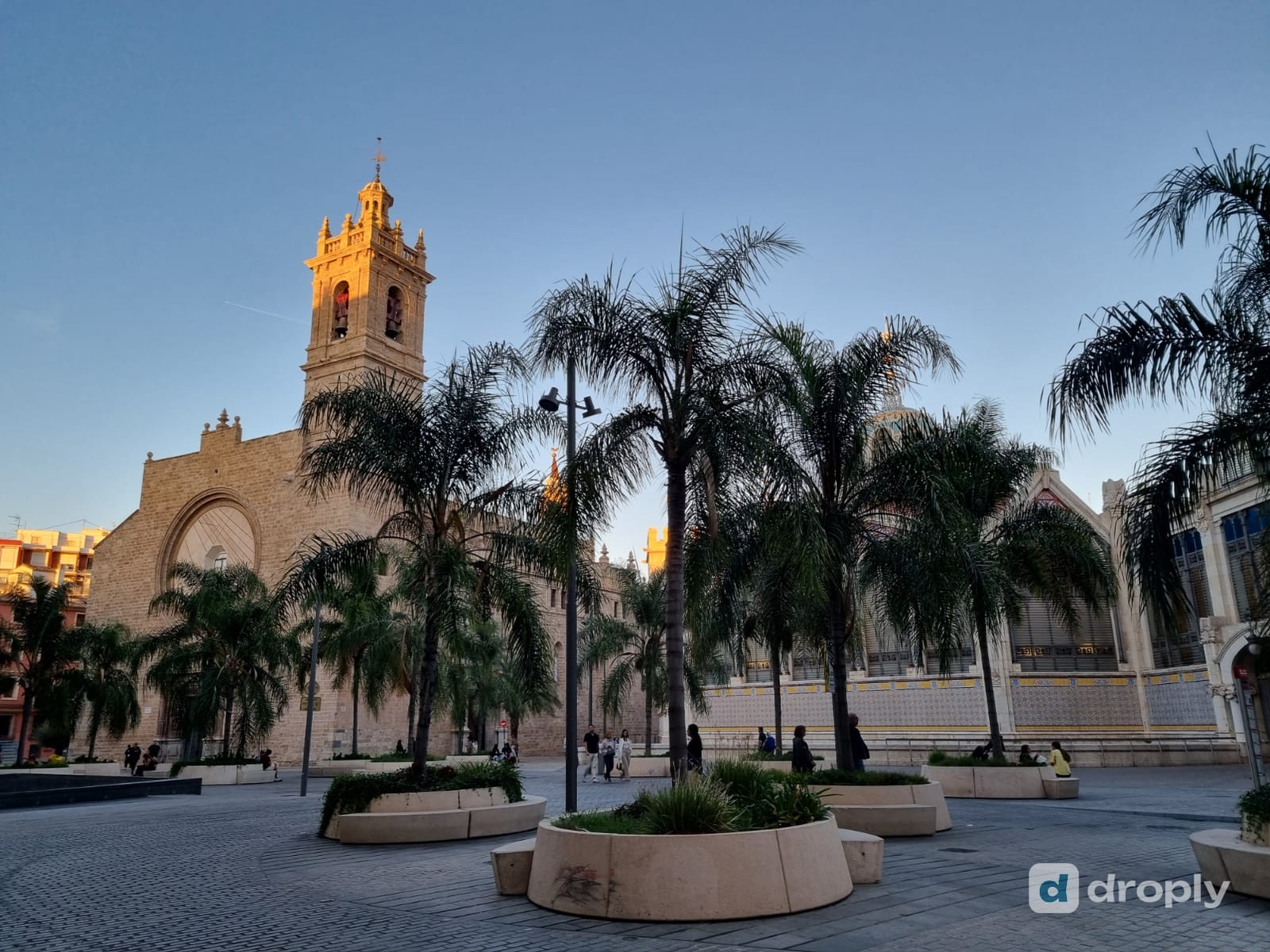 Die Kirche Sant Joan del Mercat und der Mercat Central in der Altstadt von Valencia bei Sonnenuntergang, mit Palmen auf dem Platz davor